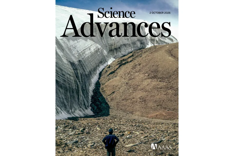 View of the Guliya Ice Cap on the Tibetan Plateau, showing a steep wall of exposed glacial ice beside rocky terrain, with a person standing in the foreground.