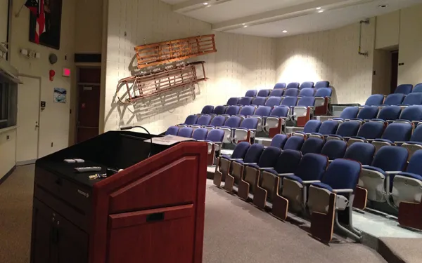 An empty auditiorium with view of the podium and many tiered seats