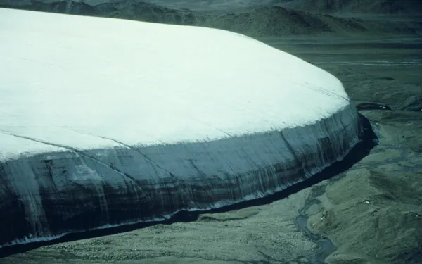 A landscape view of a massive ice cap on a dirt plateau.