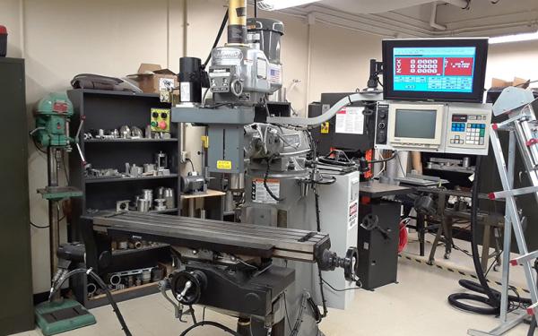 A computer numerical control milling machine (CNC mill) surrounded by other fabrication tools