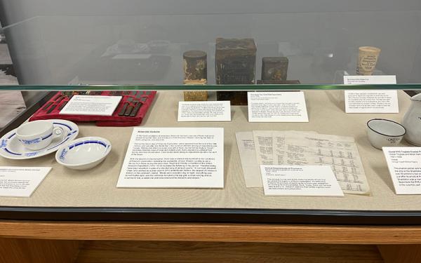 Glass enclosed exhibit containing artifacts on display in the Goldthwait Polar Library. The exhibit includes blue and white pottery as well as white documents. 