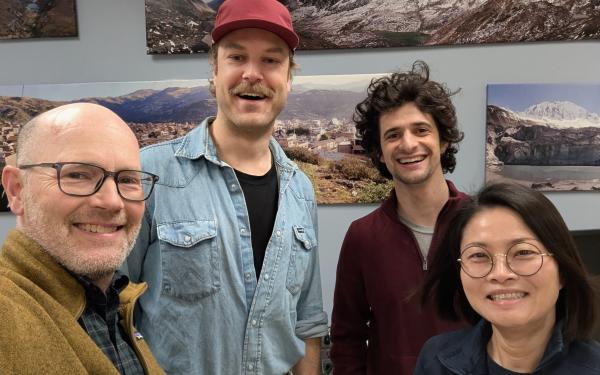 Four people indoors posing for a picture and smiling.
