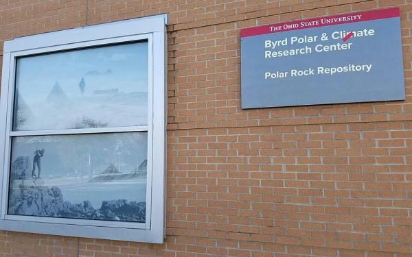 Exterior brick building  alongside a window featuring polar-themed photographic imagery of explorers and snowy landscapes.