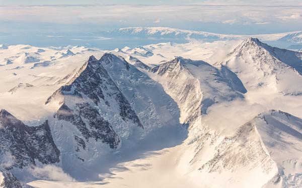 A mountain range covered in snow and ice under blue skies.