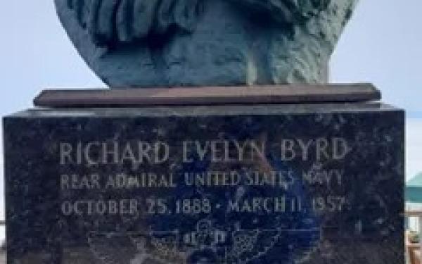 A metal statue on a pedestal with a plaque.