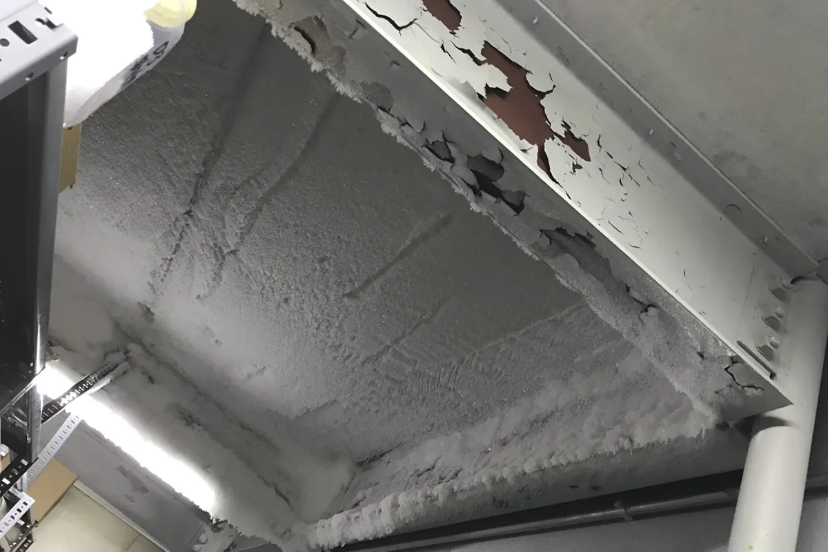 Old, peeling white paint on the ceiling is exposing a brown wall 