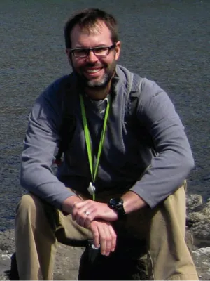Jason Cervenec sitting on a rock by the sea