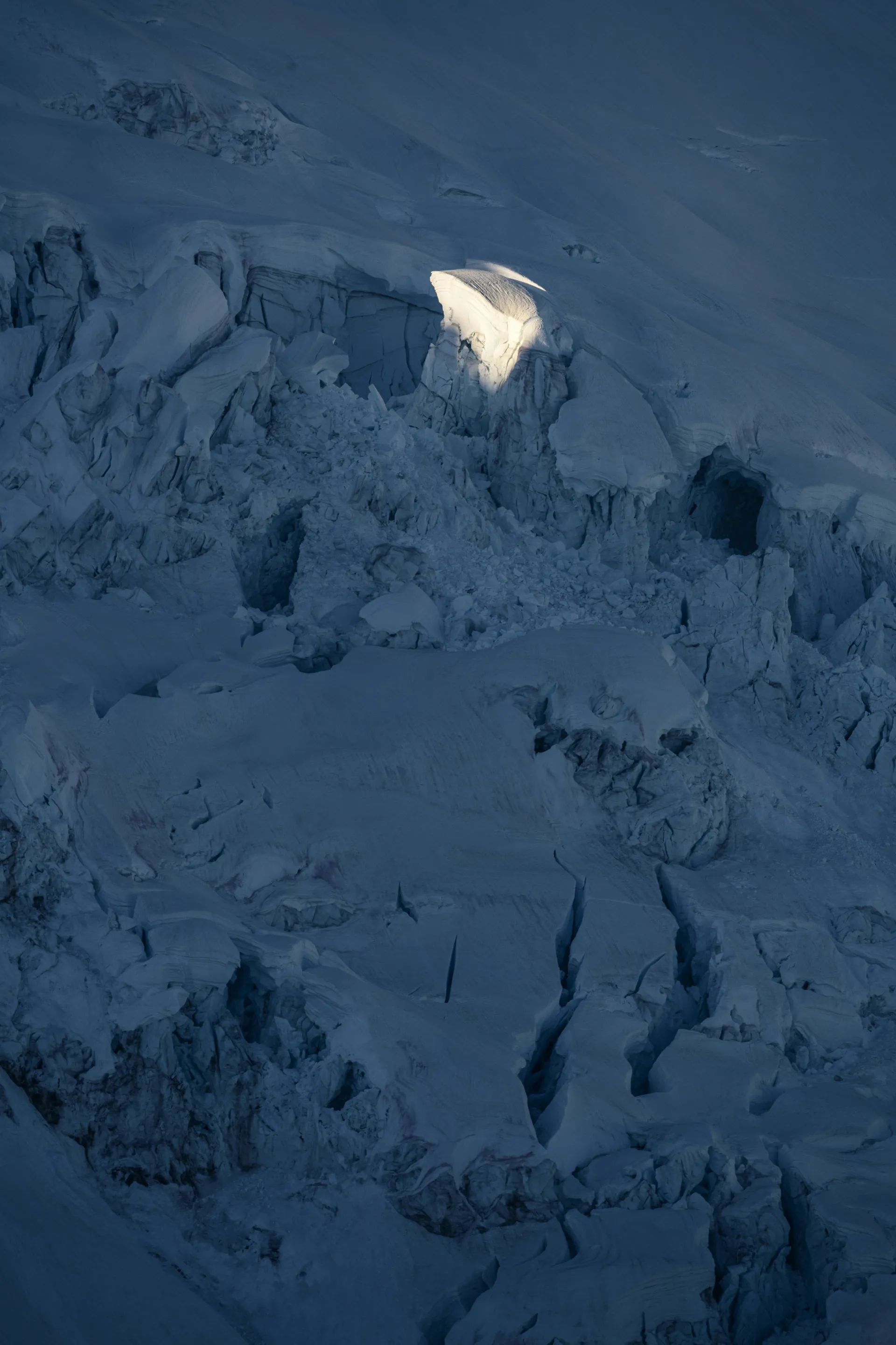 A glacier in the dark with one spot of it lit with a ray of light. 