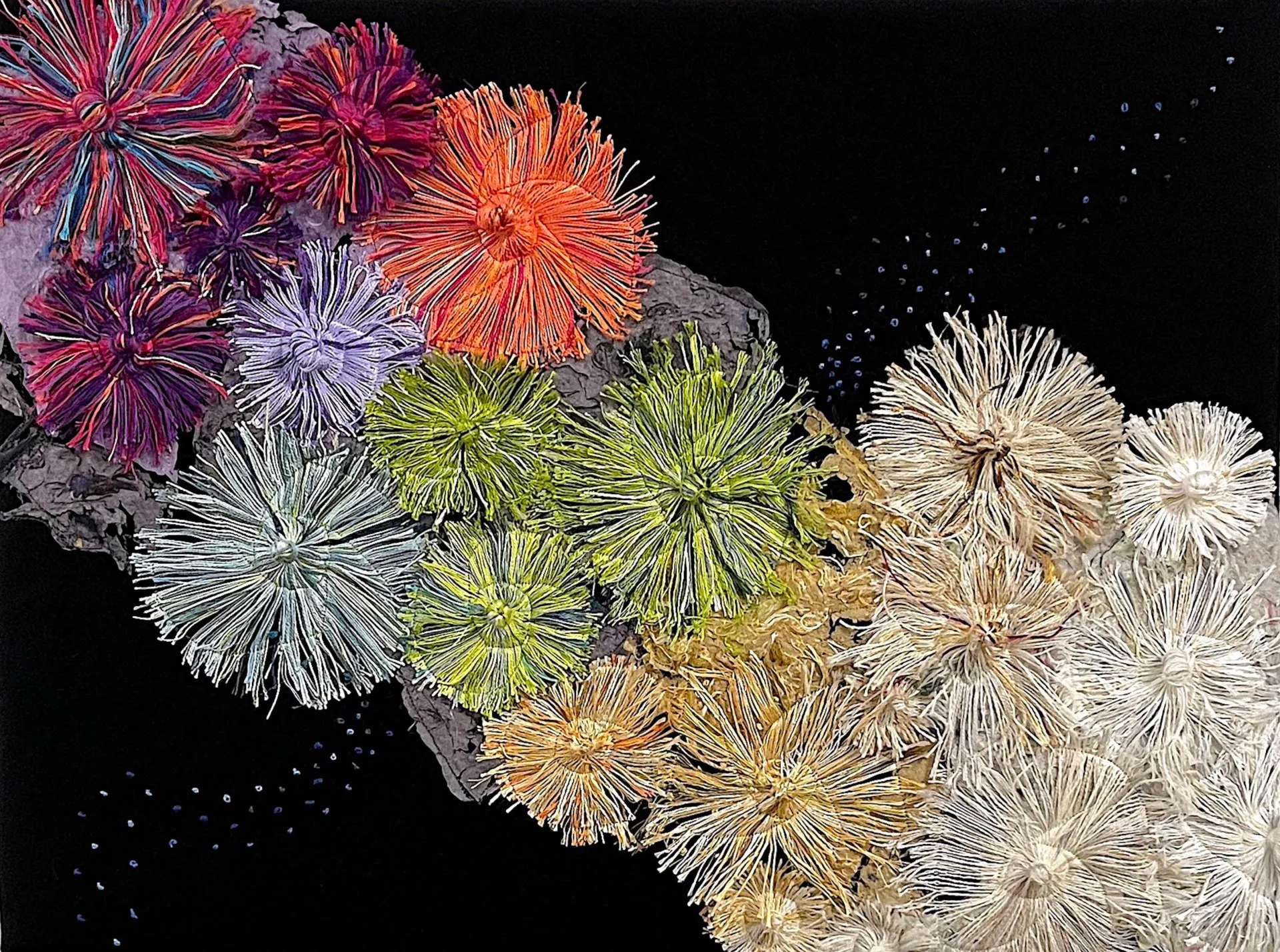 Art  handmade paper, upcycled warp yarn remnants representing Coral reef from top left to bottom right colorful coral turns to bleached coral against a black backdrop.