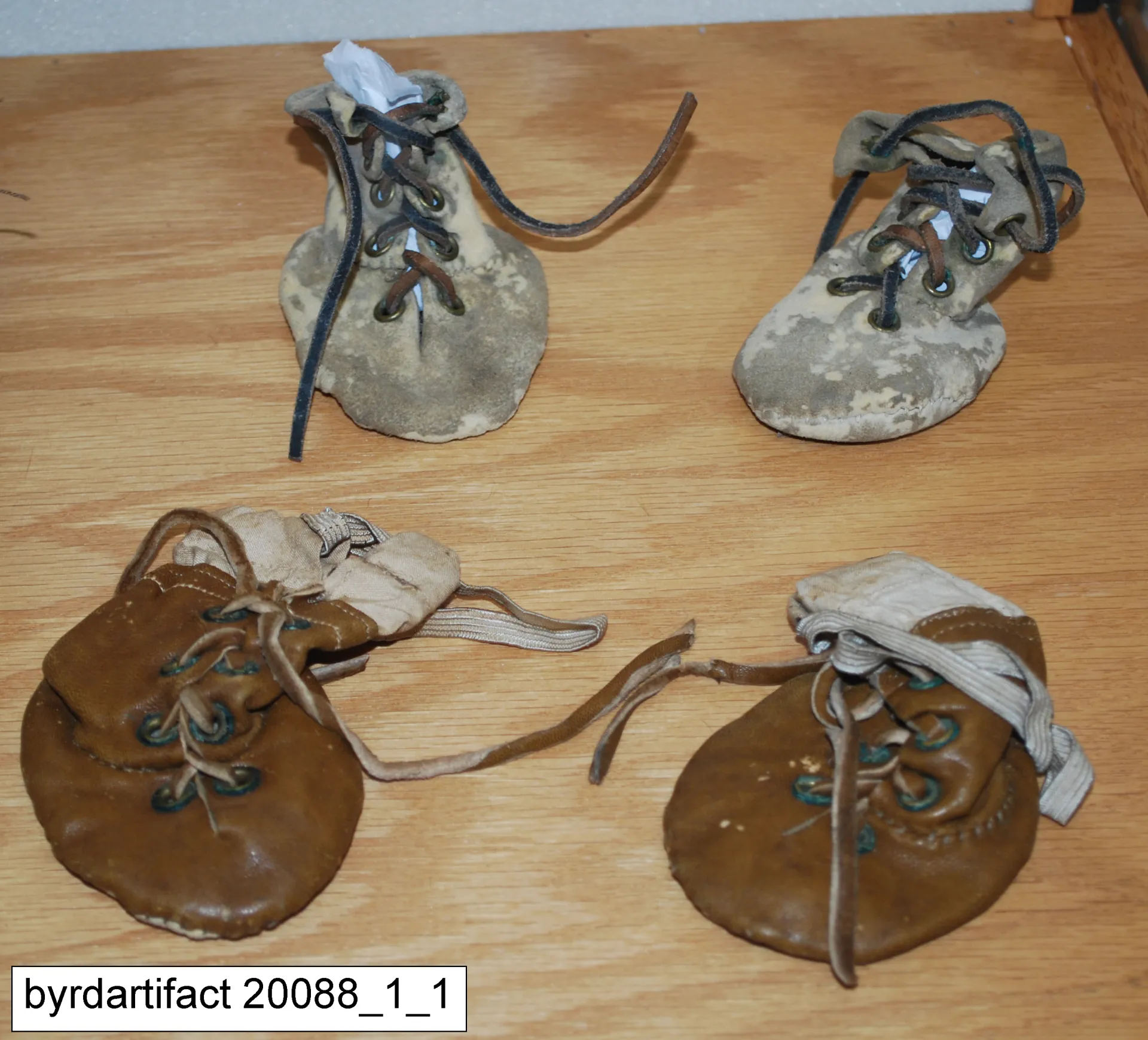 Four skin booties for a dog displayed on a wooden table.
