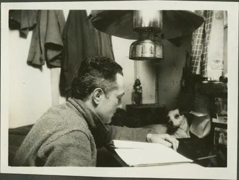 Admiral Byrd sitting at a desk with his dog Igloo.