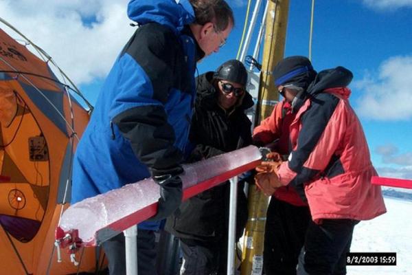 Researchers holding and researching an ice core in Quelccaya, Peru. 2003.