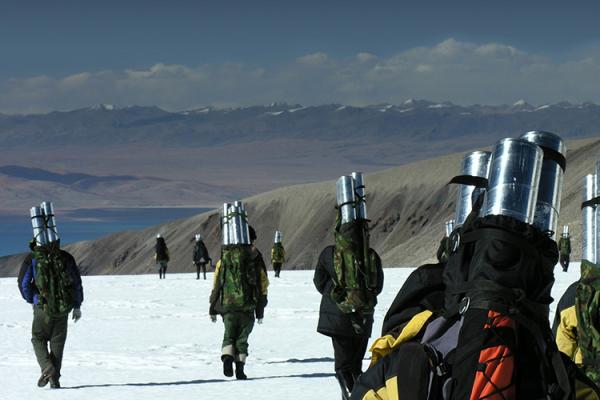 A group of people carry ice cores across the snowy landscape