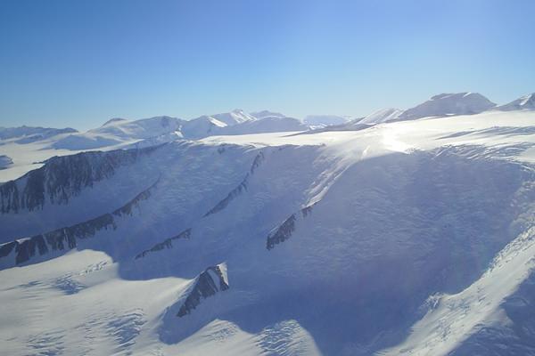 a snowy, rocky landscape brightly reflect the sunlight. The sky is clear and blue