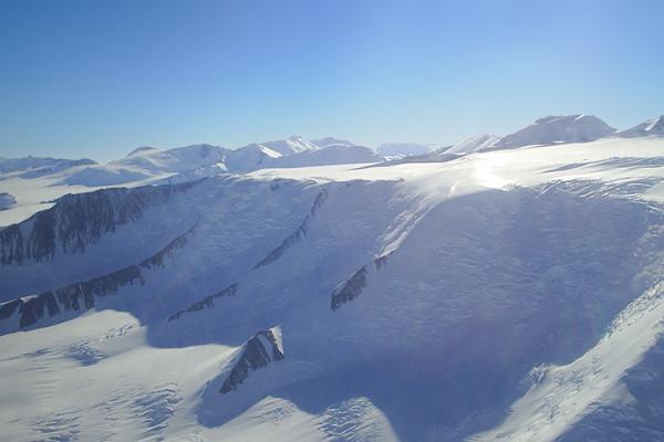 a snowy, rocky landscape brightly reflect the sunlight. The sky is clear and blue 