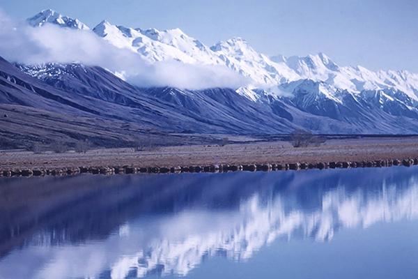 Antarctic mountain range behind a still blue lake 