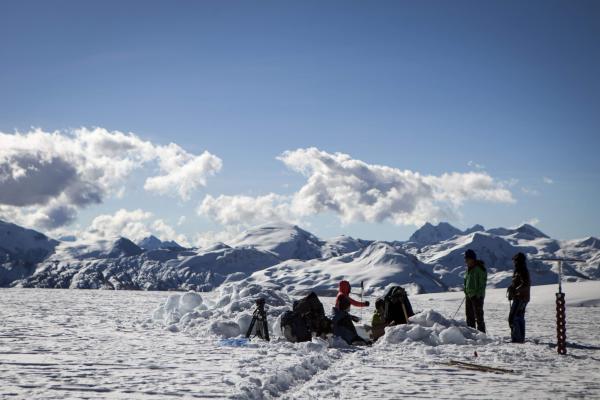 group of people working on a snowy landscape with a snowy mountain in the back 