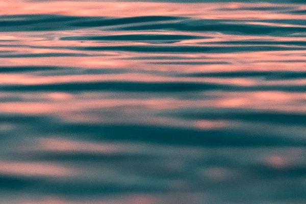 Close up of a calm body of water with the reflection of sun in it