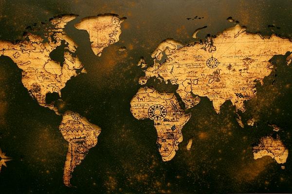 ancient looking map of continents in yellowish cream color with old writing with dark brown background