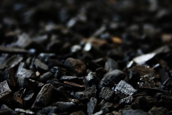 pieces of black charcoal on the ground in a dark area with little light