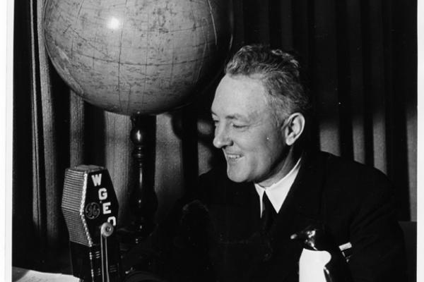 Byrd smiling at a desk and talking into a microphone