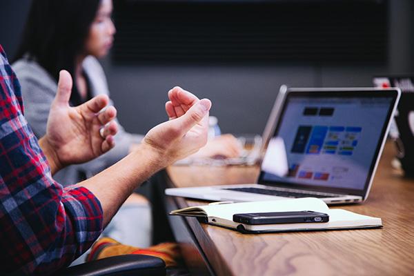 man talking in a meeting with while using computer