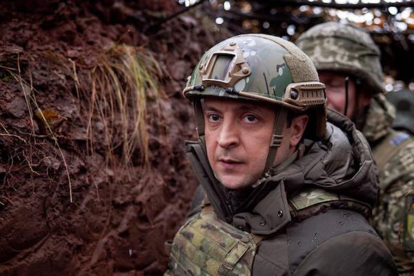 A soldier in combat gear in a muddy trench. There is another soldier behind him.