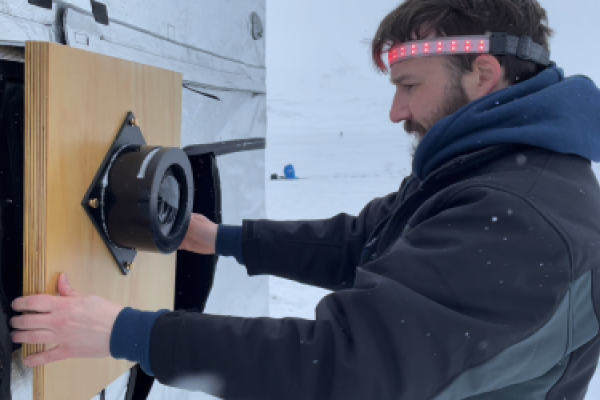 Tristan Duke, a man in a headlamp and winter jacket, repositions his scientific instrument 