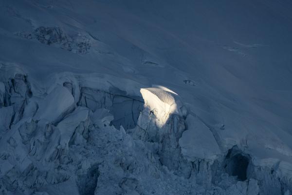 A glacier in the dark with one spot of it lit with a ray of light. 