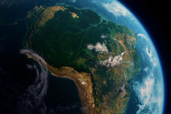 Satellite view of South America with visible lush greenery and cloud formations over the continent, set against the backdrop of Earth's curvature.