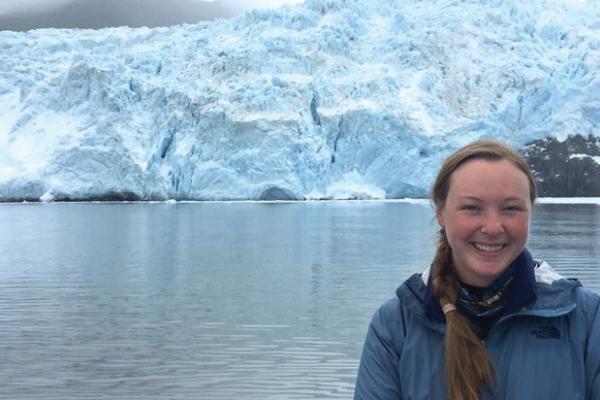 Person smiling in front of a large glacier.