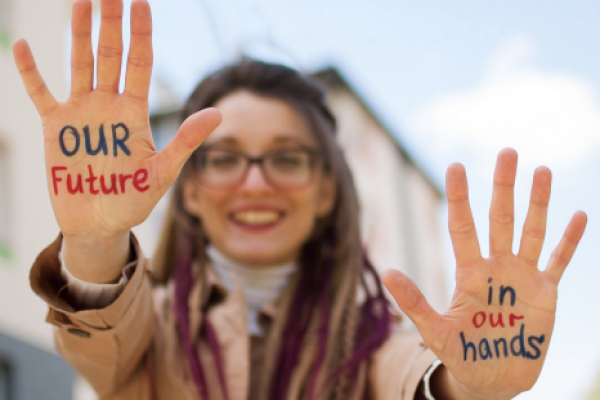 A girl with painted hands that say "our future in our hands"