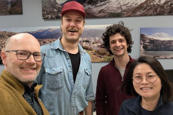 Four people indoors posing for a picture and smiling.