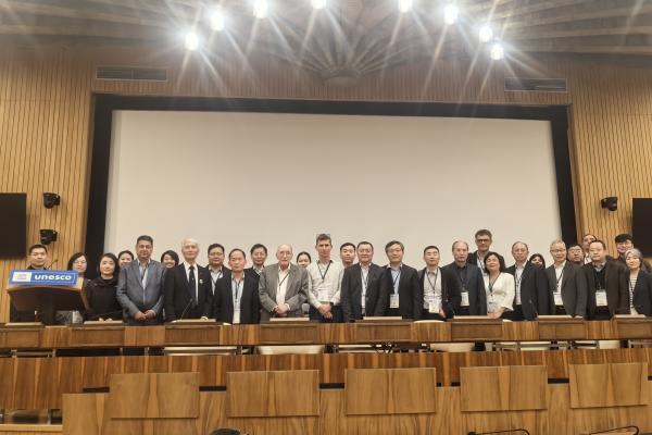 Group of individuals posing for a photo in a conference room with a UNESCO podium.