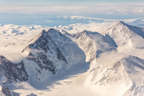A mountain range covered in snow and ice under blue skies.