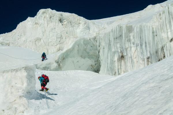 Two polar explorers climbing an icy slope at night