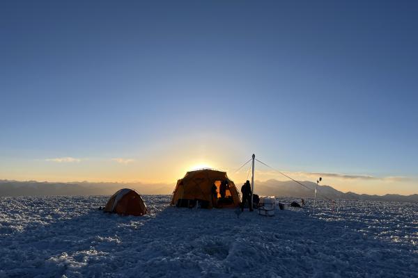 The sun peaks out from behind a basecamp tent 