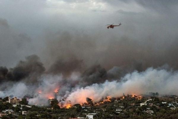 A helicopter flies over smoke from a burning forest