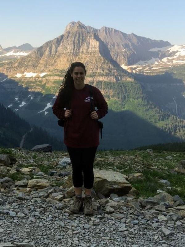 girl standing holding a backpack on a hiking trail