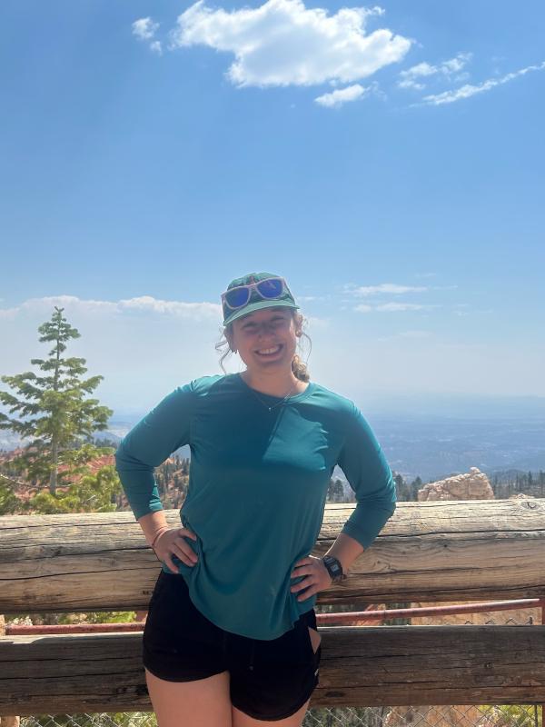 Eliza Smith wearing athletic clothing in front of a small tree with a bright blue sky. 