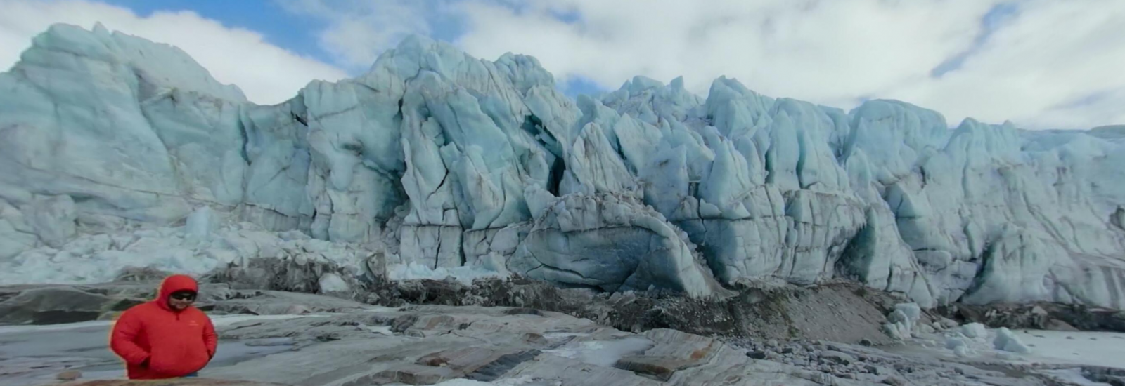 researcher in a bright red coat at the edge of a glacier