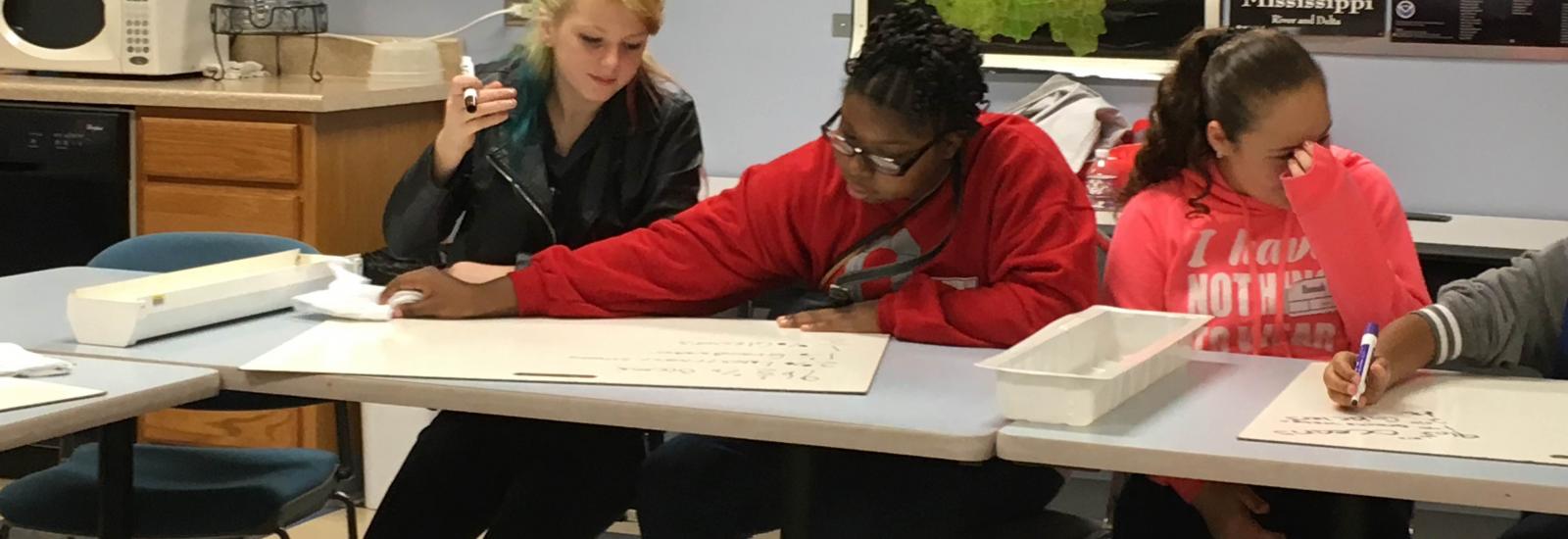 three students sitting at a table having a discussion in the Byrd Polar and Climate research center