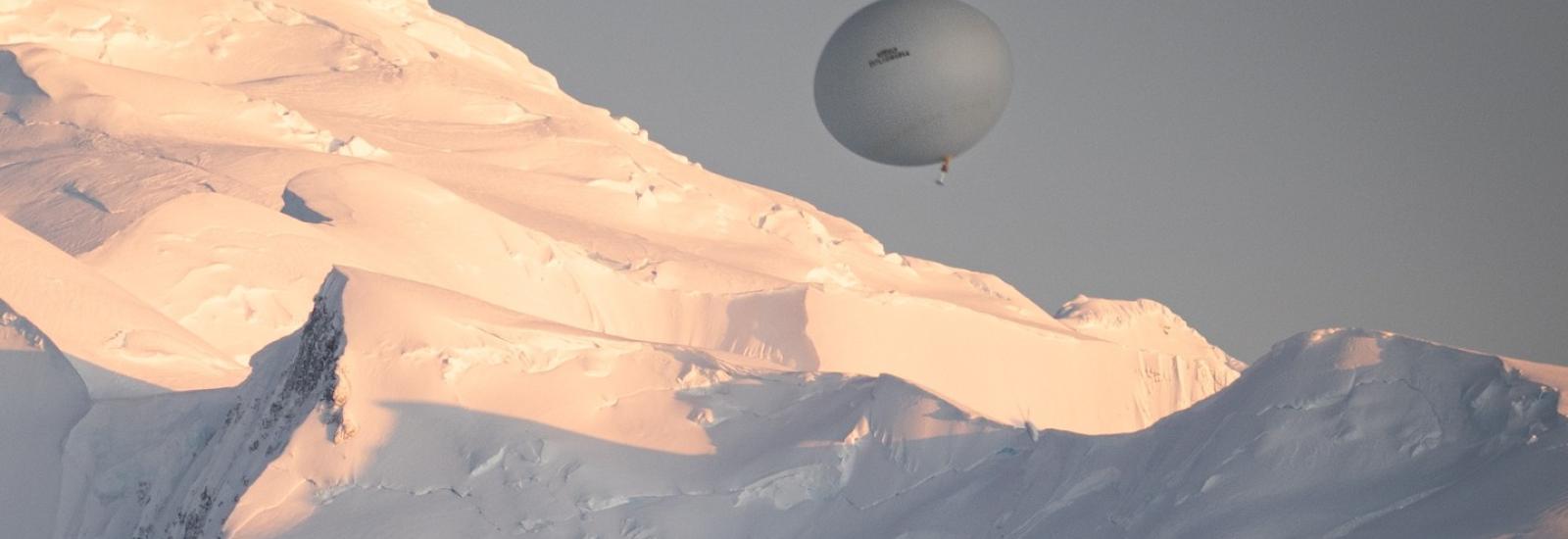 White Balloon in the sky with snowy mountains