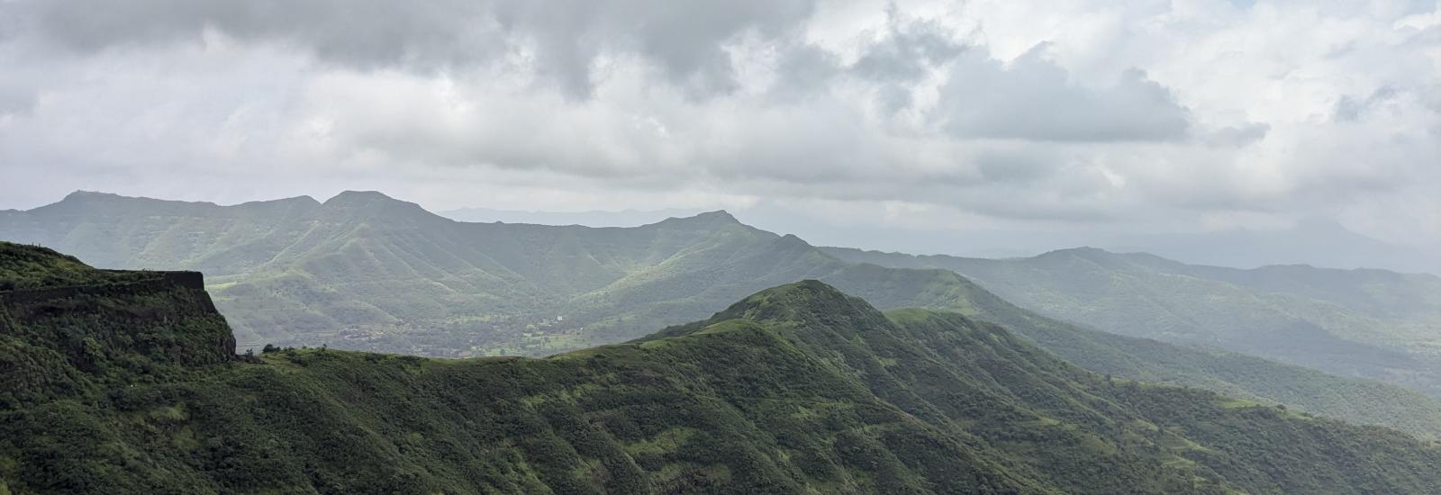 view of green mountains under white clouds at a distance