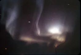 Dark, night sky with a white aurora in the center.