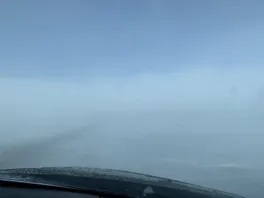 Blowing snow covering the road taken from inside the car front windshield