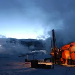 Ice core drilling at night. the landscape is dark except for a lit up shelter 