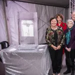 An ice sculpture on a table on the left and from left to right Georgie Shockey, her mother wearing red, Ellen Mosley Thompson, Georgie's partner, John,  Lonnie Thompson and  Georgie's father standing Georgie, Ellen and her dad clutching their hands together while Lonnie's hand is on her father's shoulder 