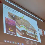 Tom Darrah presenting via Zoom in big screen.