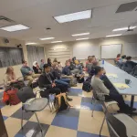 A seated audience listening to a presentation.